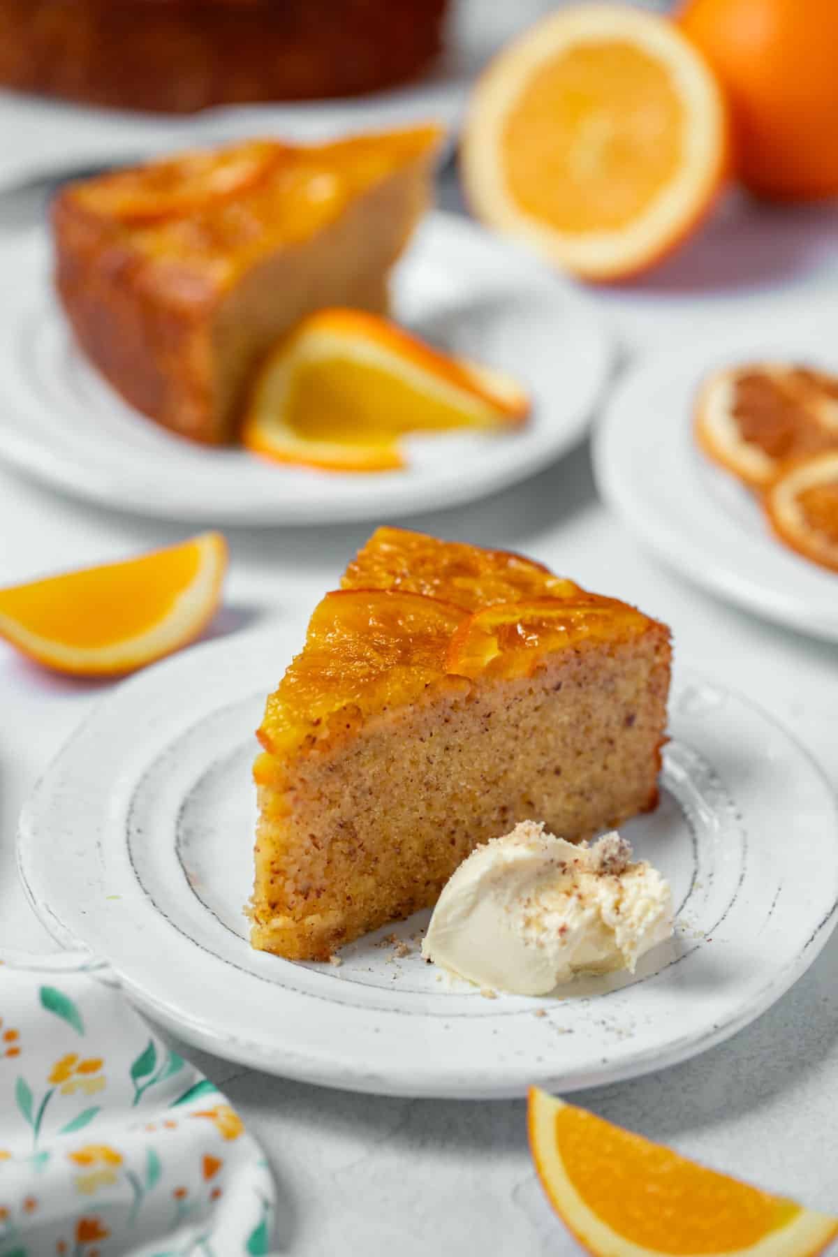 a piece of orange cake on a plate with cream and orange slices.