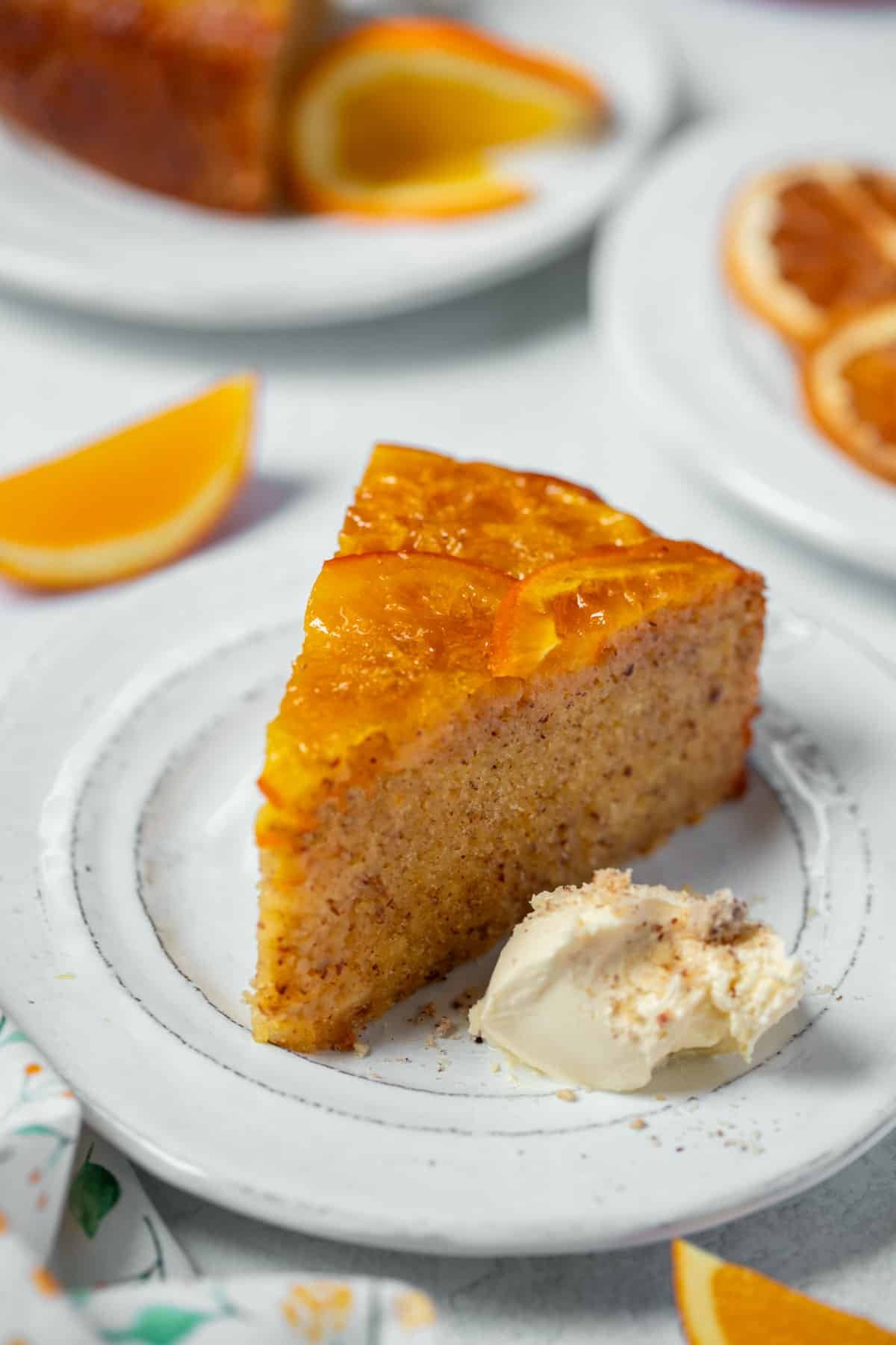 a slice of orange cake on a plate, with whipped cream.