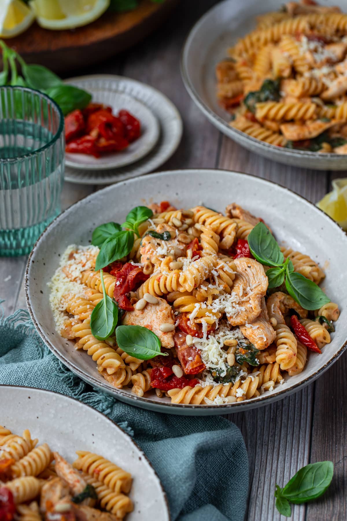 bowls of pasta on a table with basil and cheese.