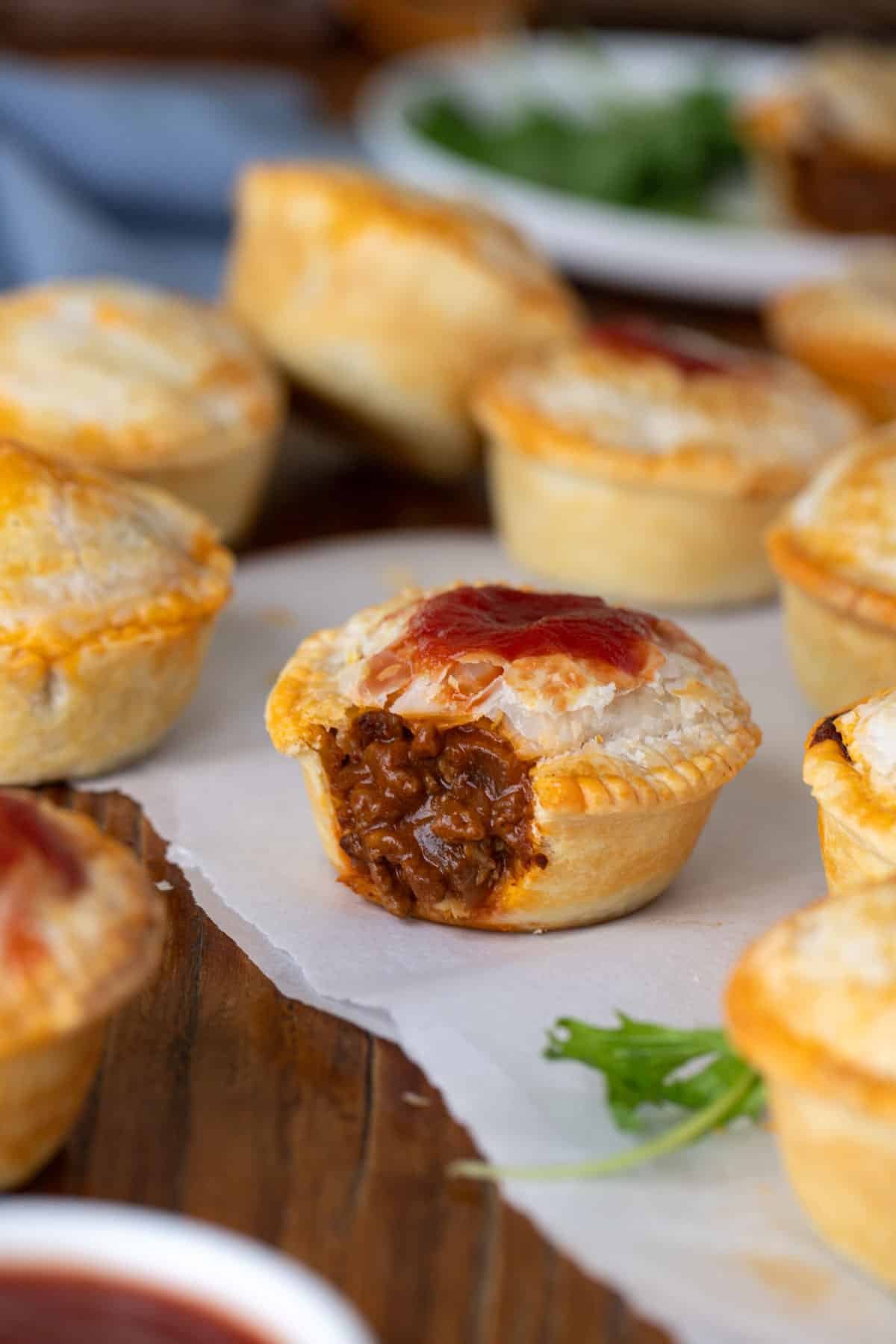 mini pies arranged on a table, topped with tomato sauce.