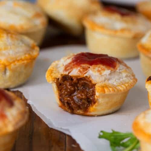 beef party pies on a table topped with tomato sauce.