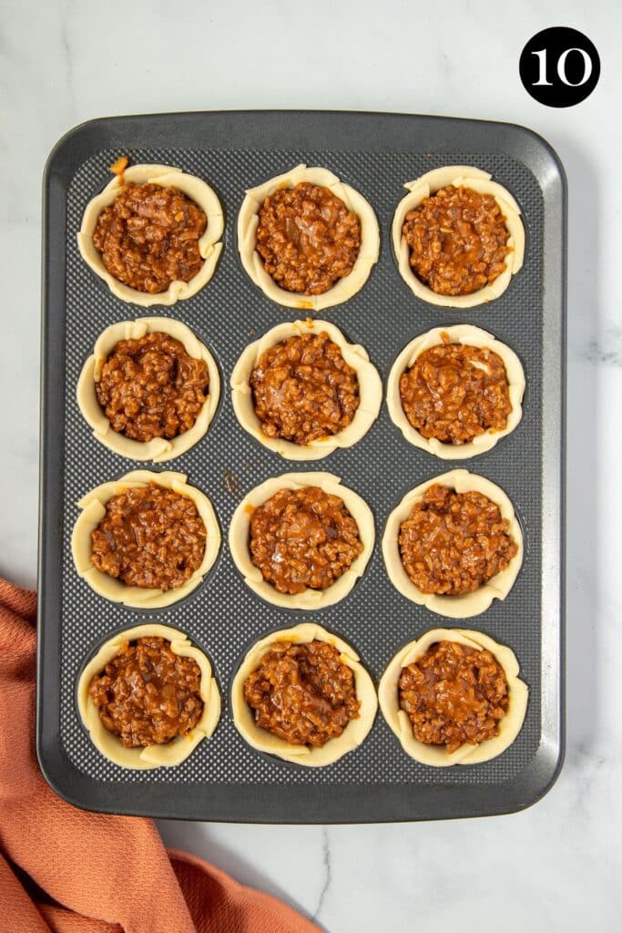 pastry bases in a muffin tin, filled with beef mince filling.
