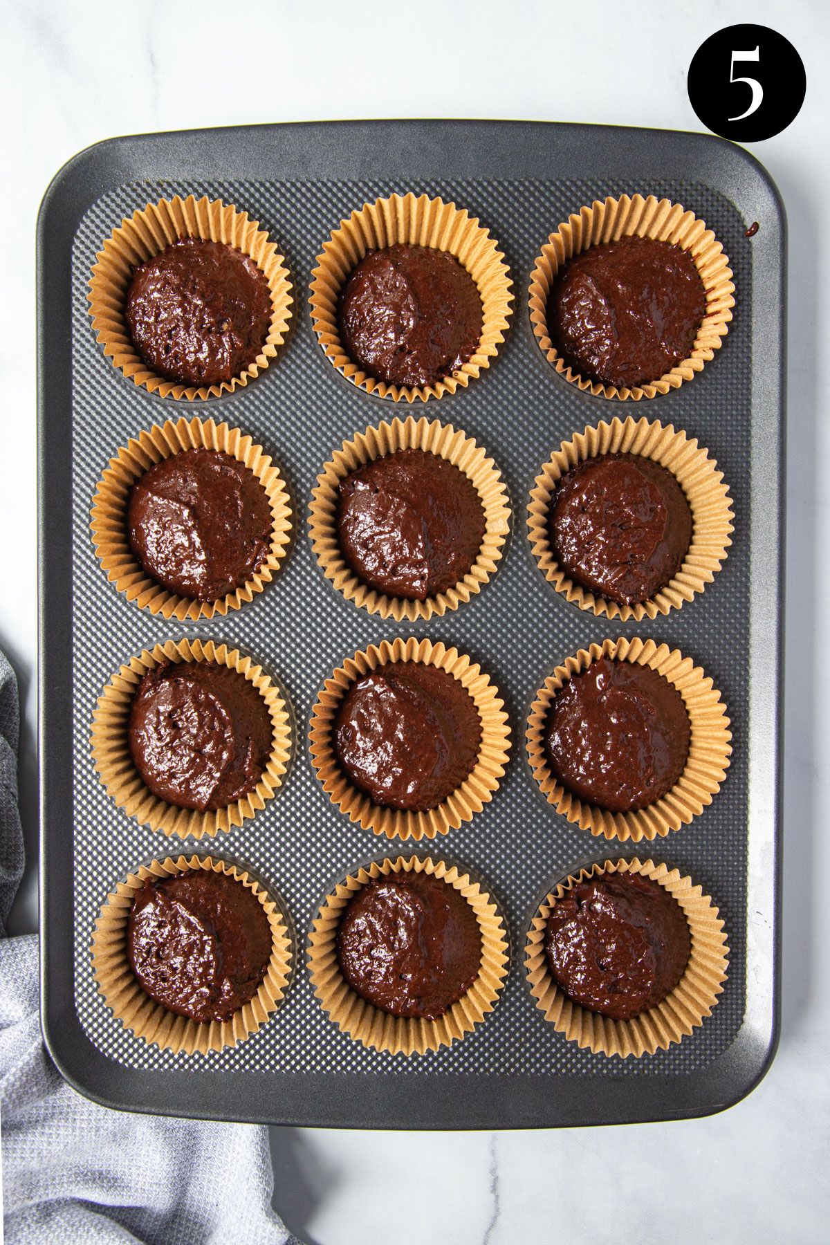 cupcake mixture in a cupcake tray lined with paper cases.