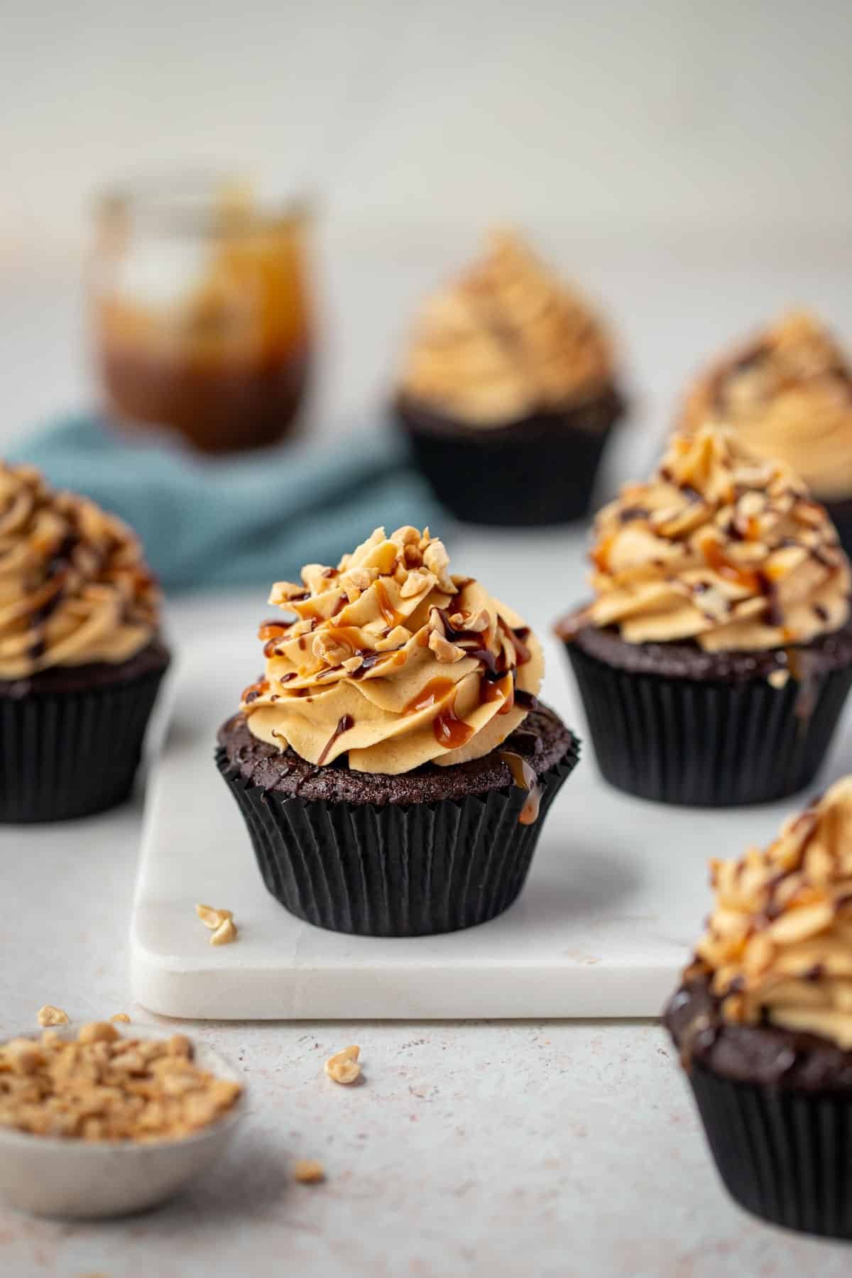 cupcakes on a bench topped with frosting and peanuts.