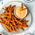 sweet potato fries on a plate with a bowl of dipping sauce.