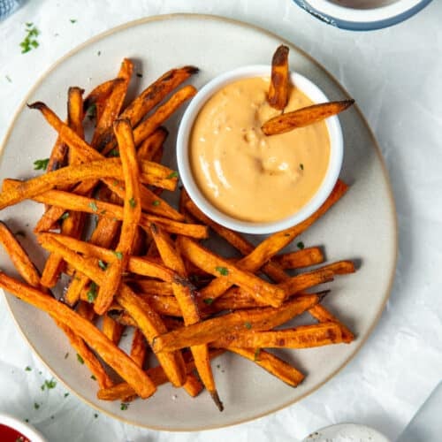 sweet potato fries on a plate with a bowl of dipping sauce.