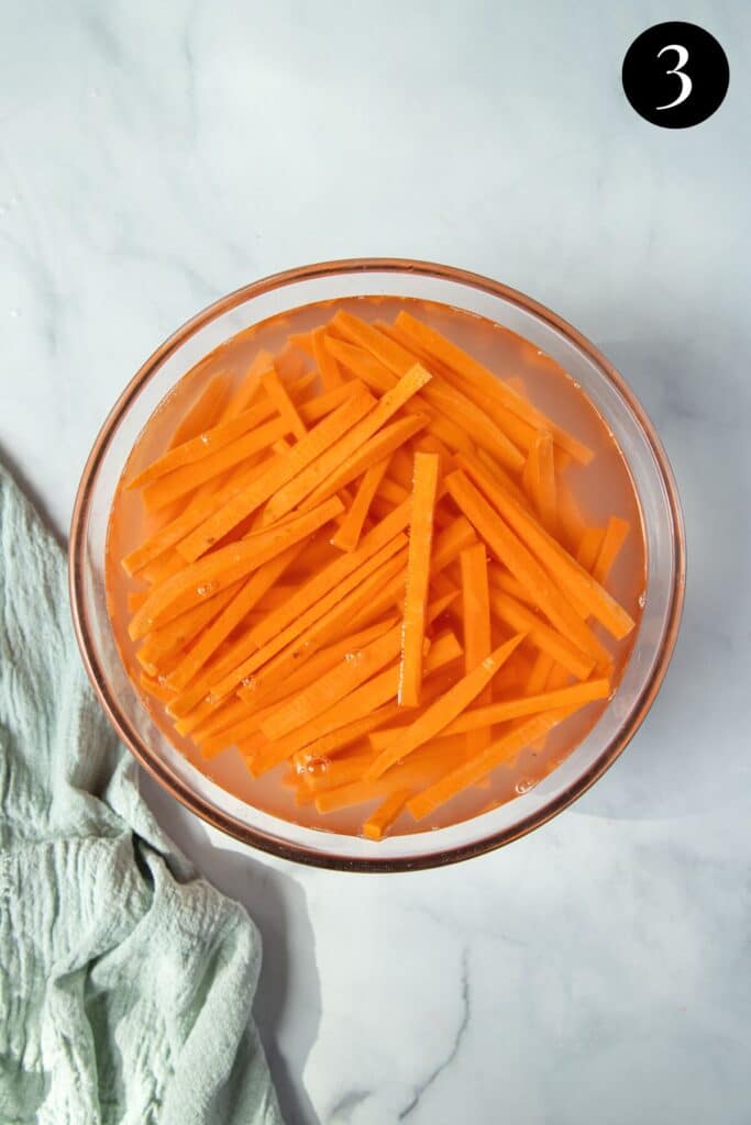 sweet potato fries soaking in a bowl of water.