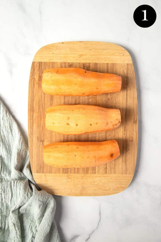 peeled whole sweet potatoes on a wooden board.