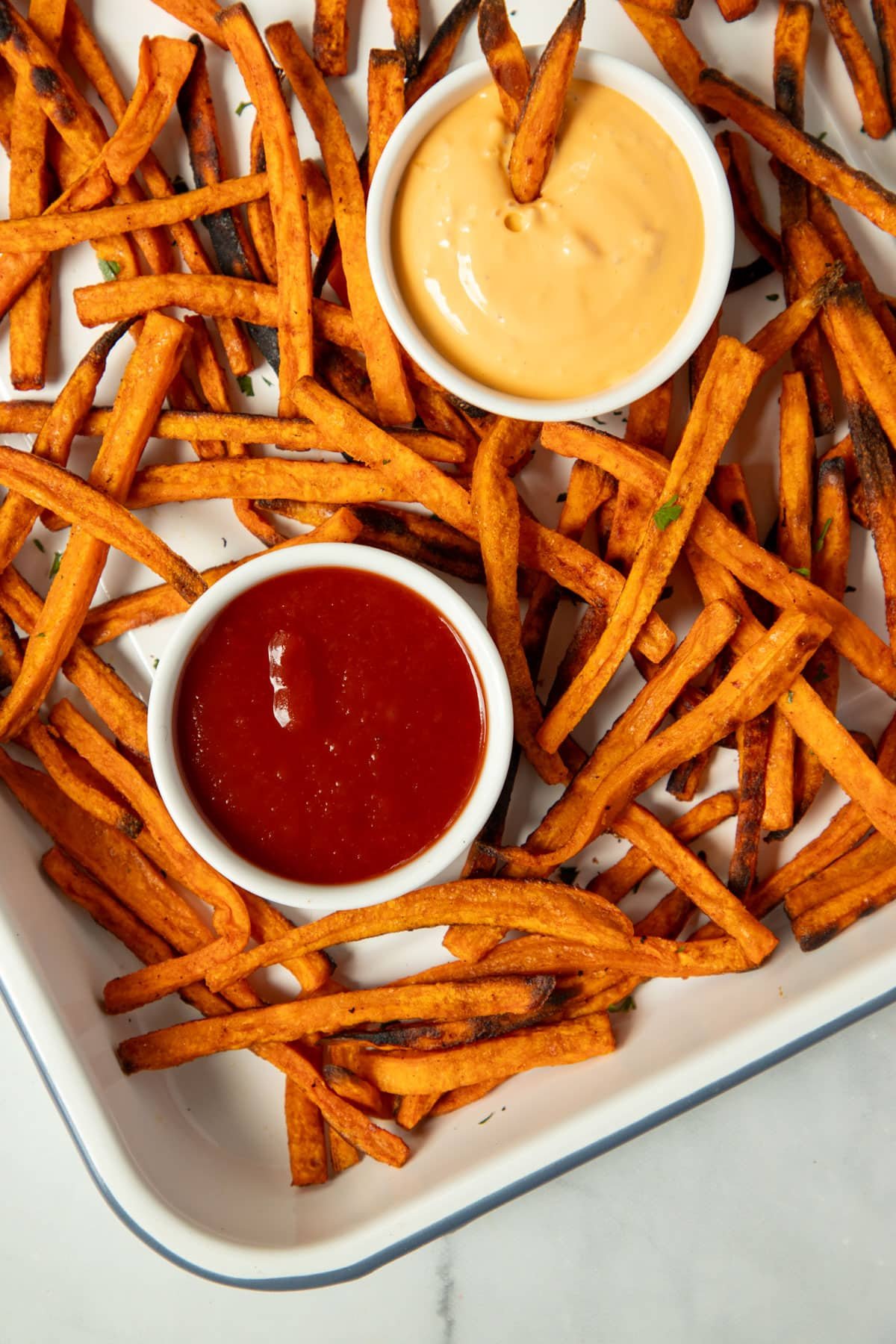 sweet potato fries on a tray with bowls of dipping sauce.