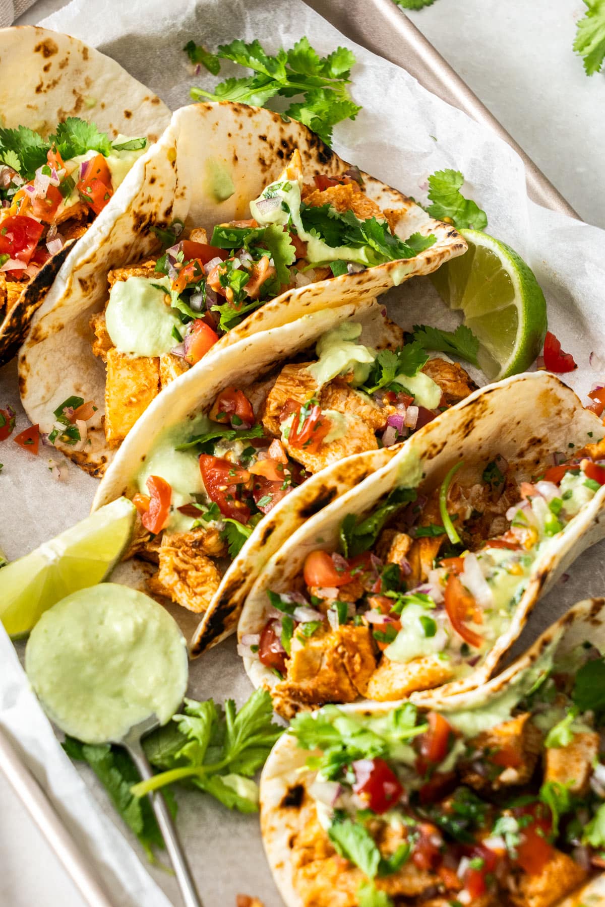 tacos arranged on a tray with lime wedges.