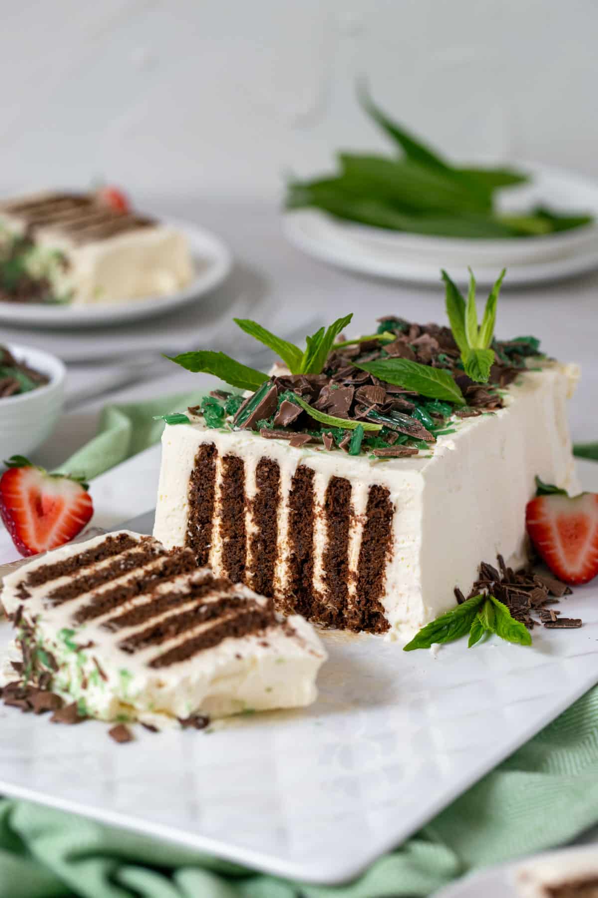 chocolate ripple cake on a white plate with mint and strawberries.