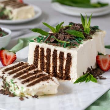 chocolate ripple cake on a white plate, topped with peppermint and chocolate.