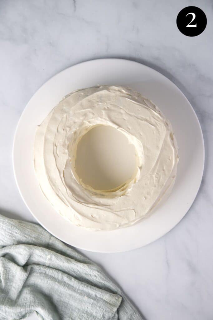 a chocolate ripple wreath covered with cream on a serving plate.