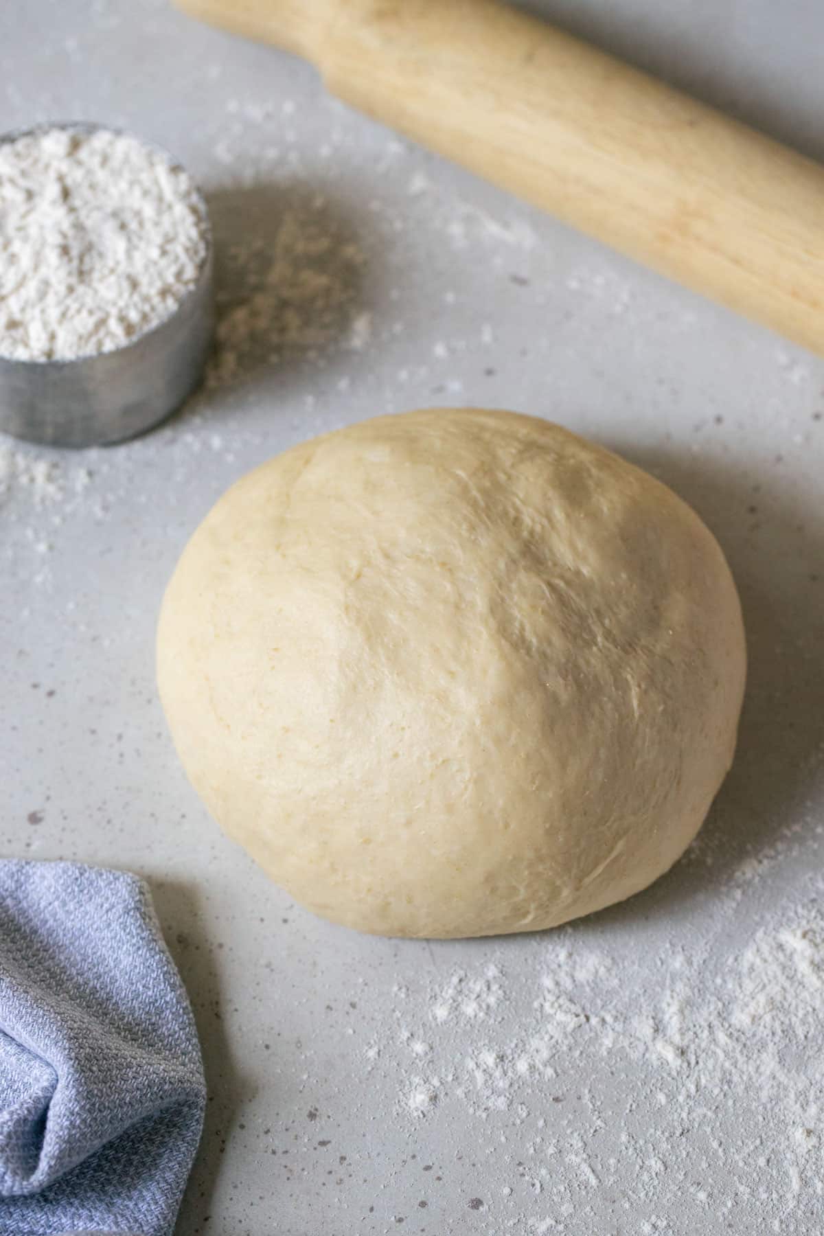 a ball of pizza dough on a table with flour and a rolling pin.
