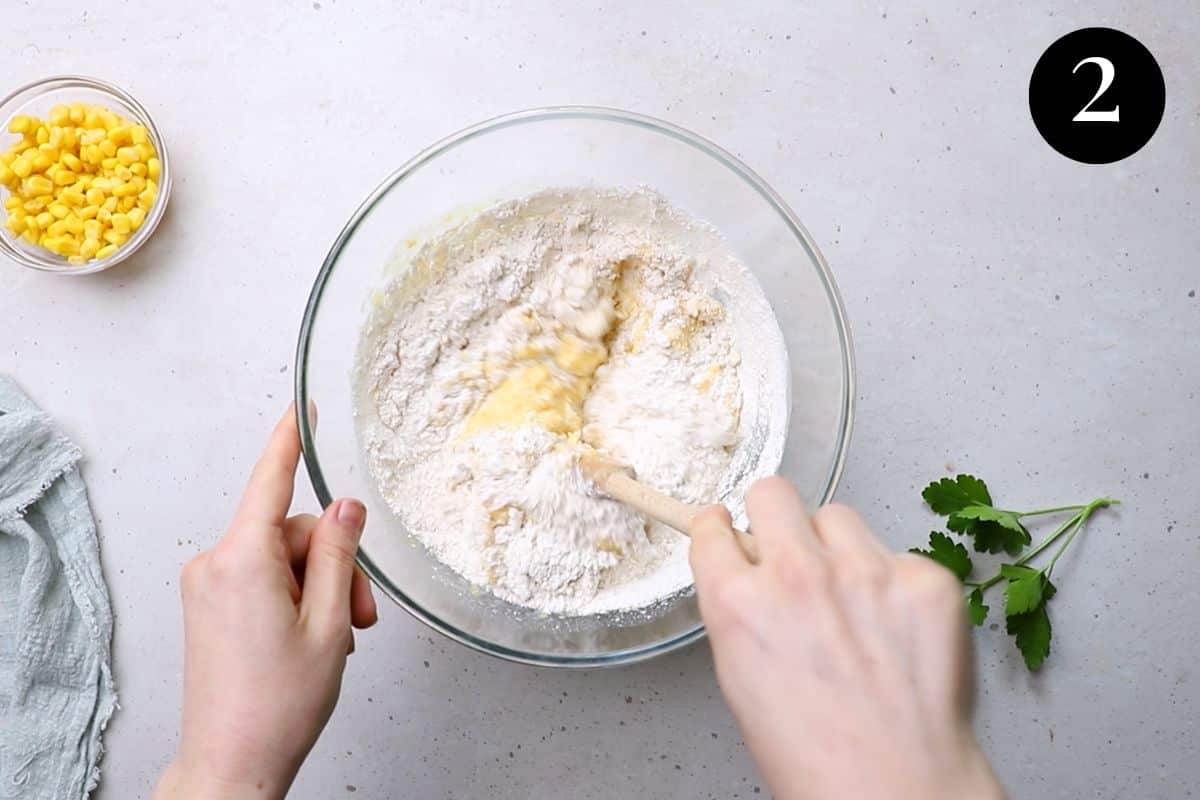 flour being added to creamed corn mixture in a bowl.