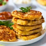 a pile of corn fritters on a plate with sauce.