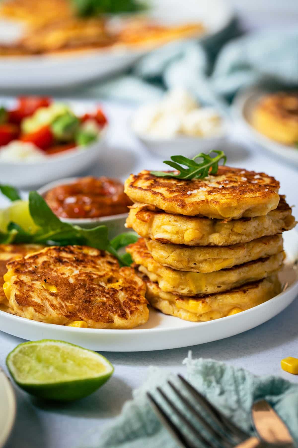corn fritters on a plate with lime and salad.