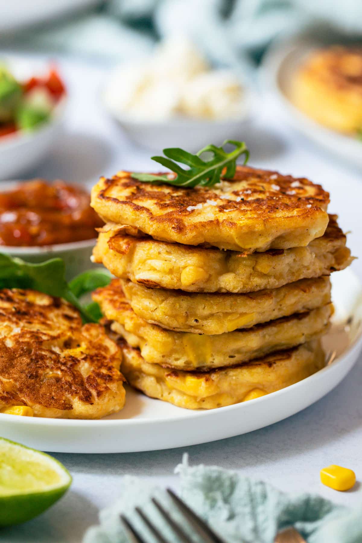 a pile of corn fritters on a plate with rocket.