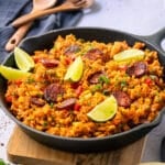 a pan filled with rice, chorizo and topped with lime wedges.