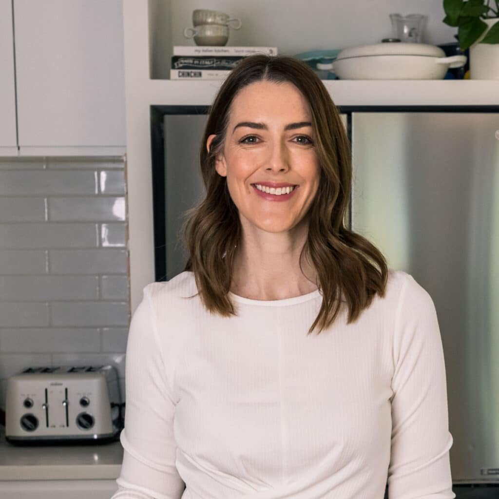 a smiling woman standing in a kitchen.