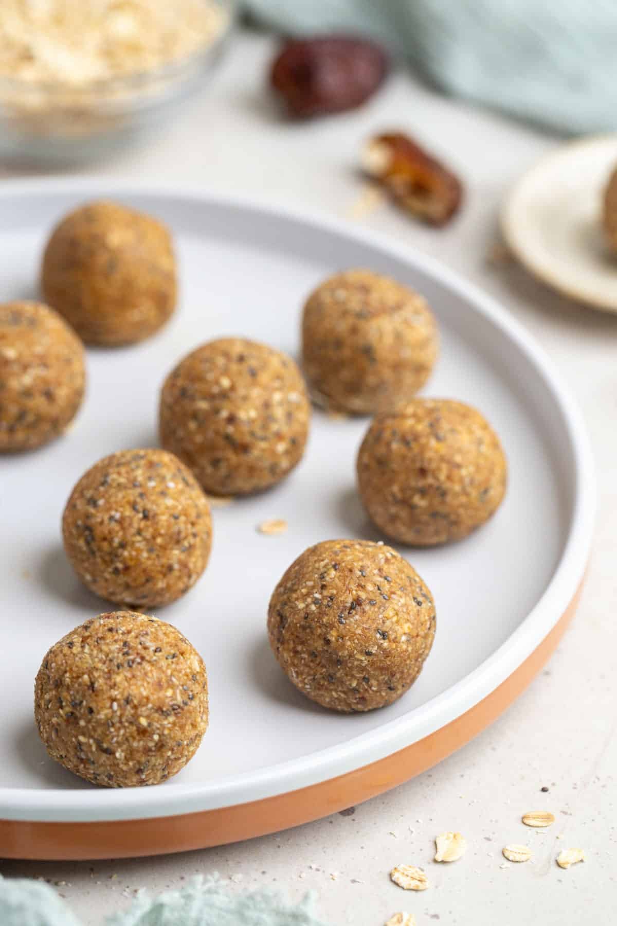 caramel bliss balls on a white plate, with oats.