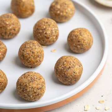 bliss balls on a white plate, with sprinkled oats.