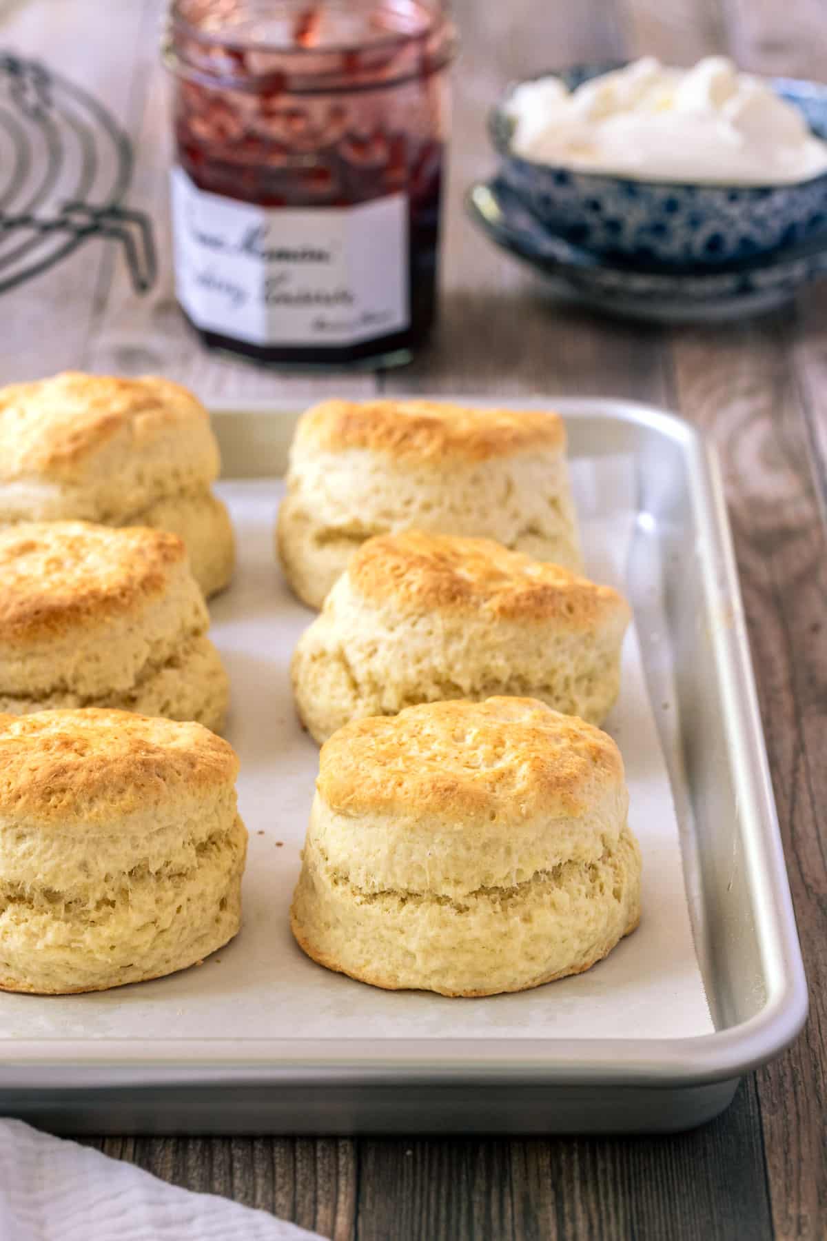 a tray of scones on a table with jam and cream.