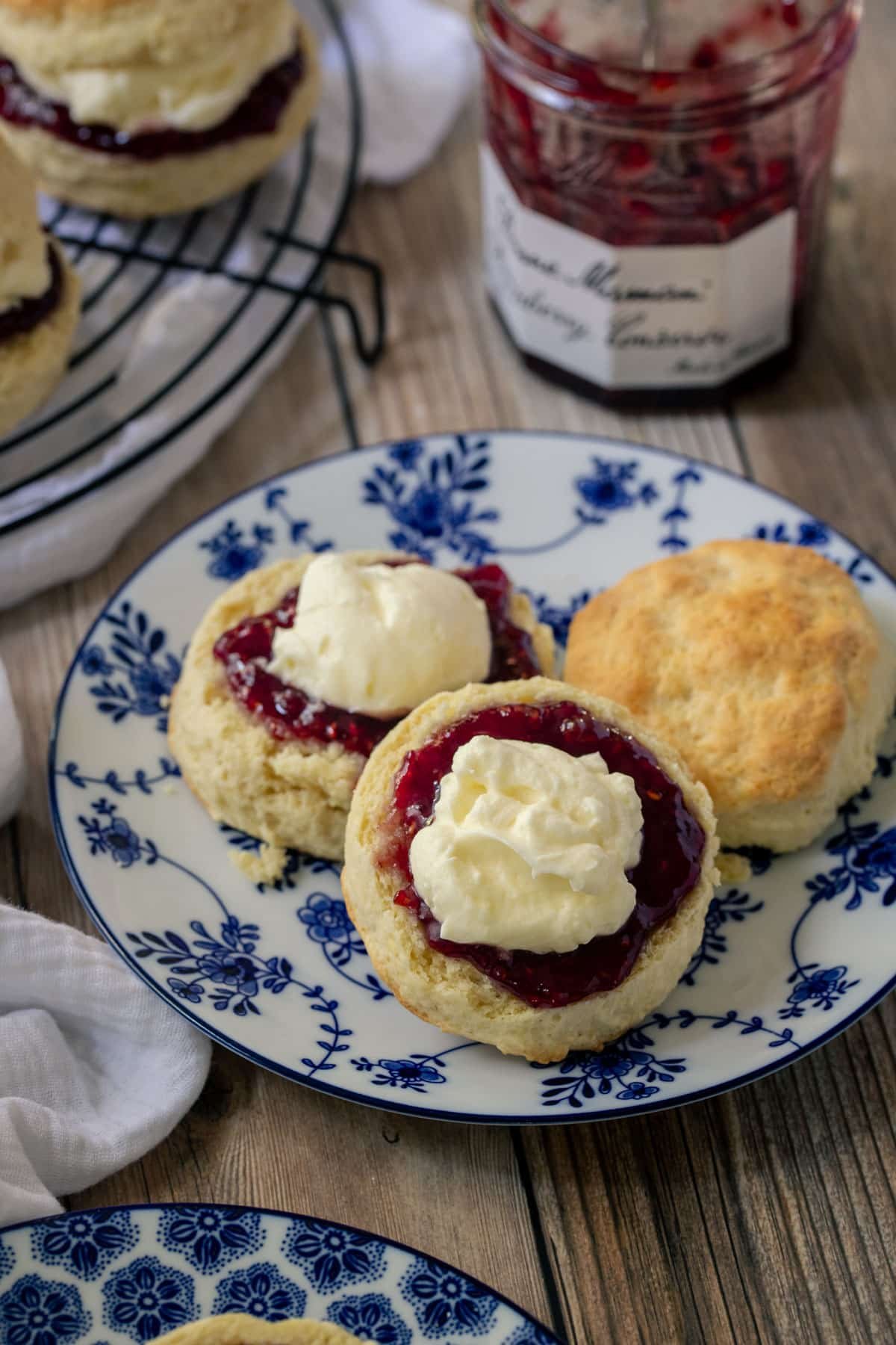 a plate of scones, cut in half and topped with jam and cream.
