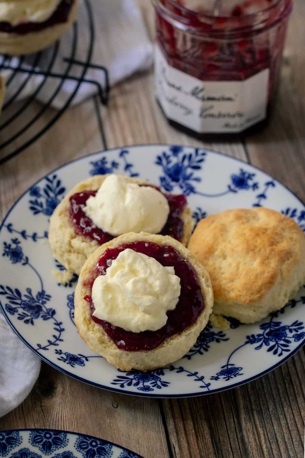 a plate of scones, topped with jam and cream.