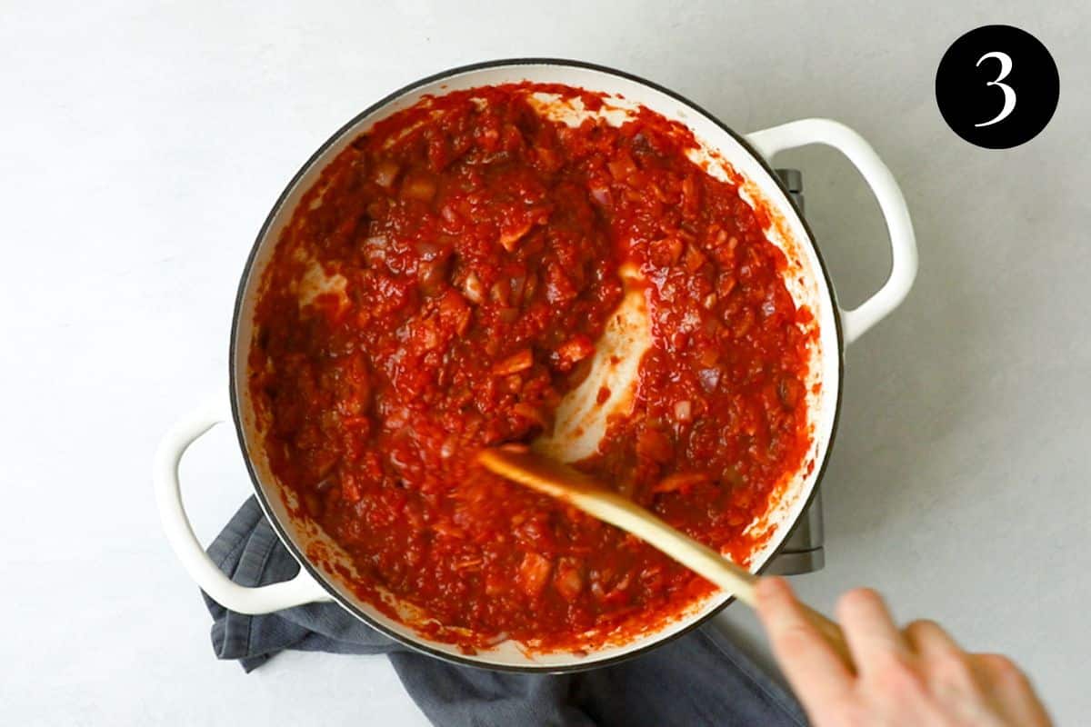 tomato sauce being simmered and stirred in a pan.