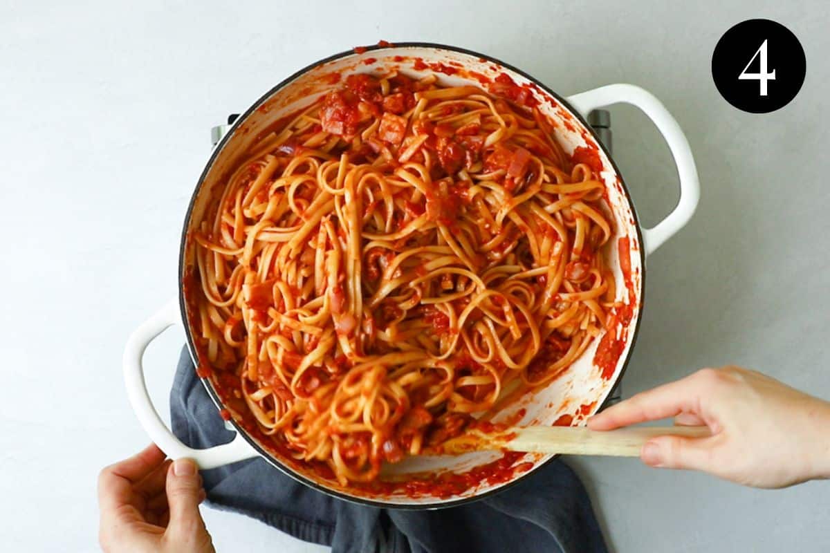 tomato and bacon pasta being stirred in a pan.