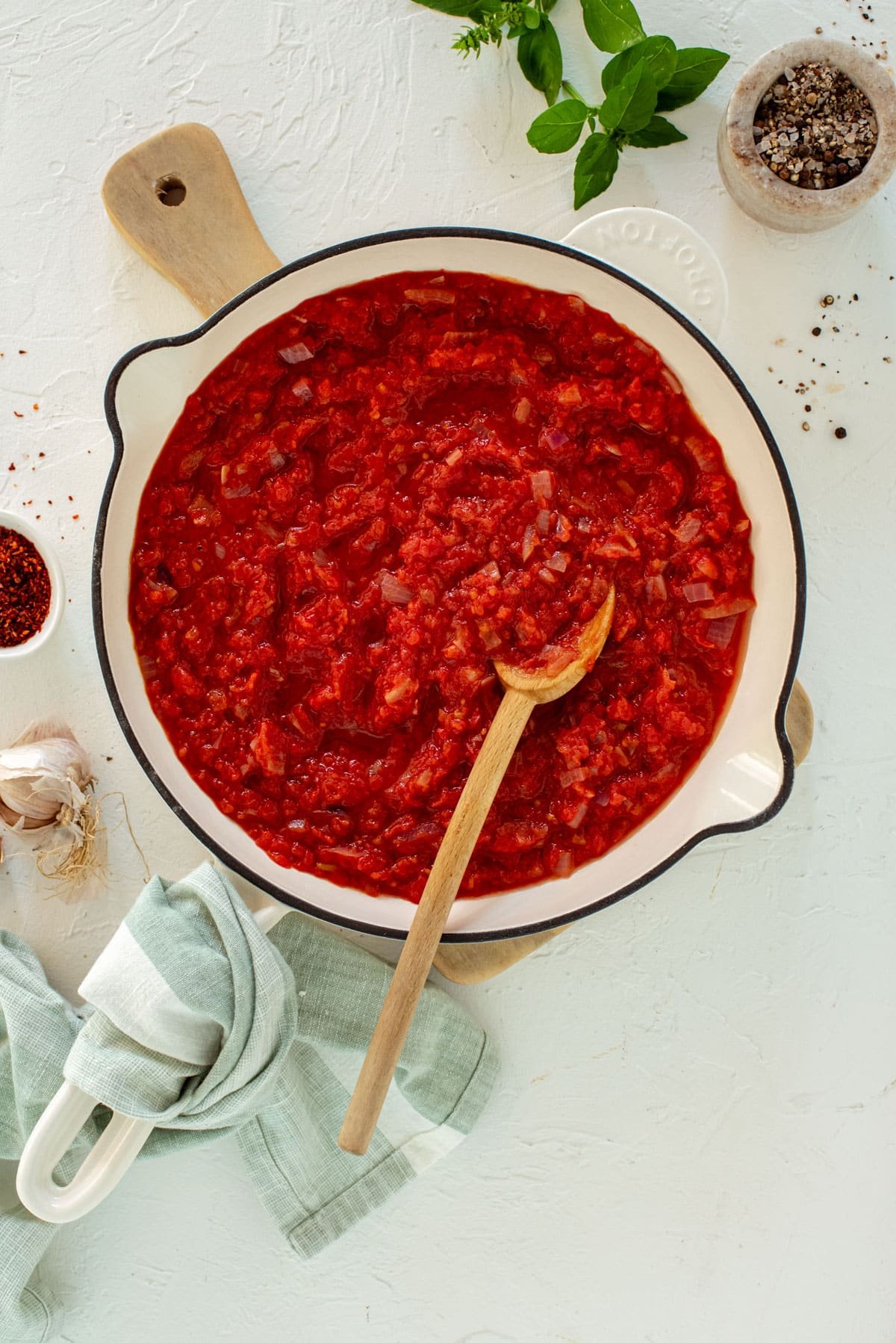 a pan with red tomato sauce. A wooden spoon is in the sauce.