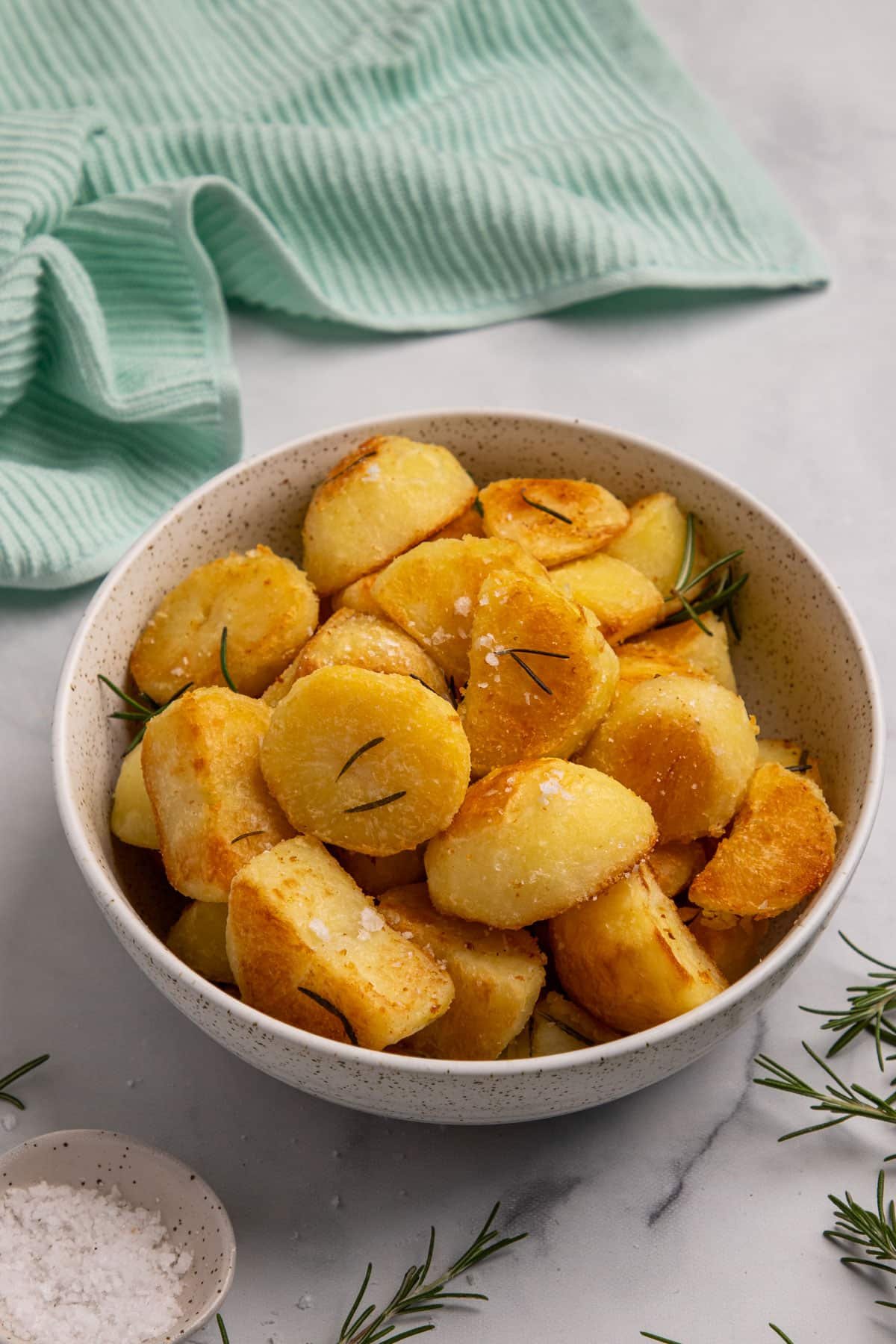 a bowl of golden roast potatoes on a table.