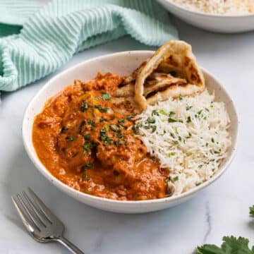 a bowl of tikka masala and rice on a table.