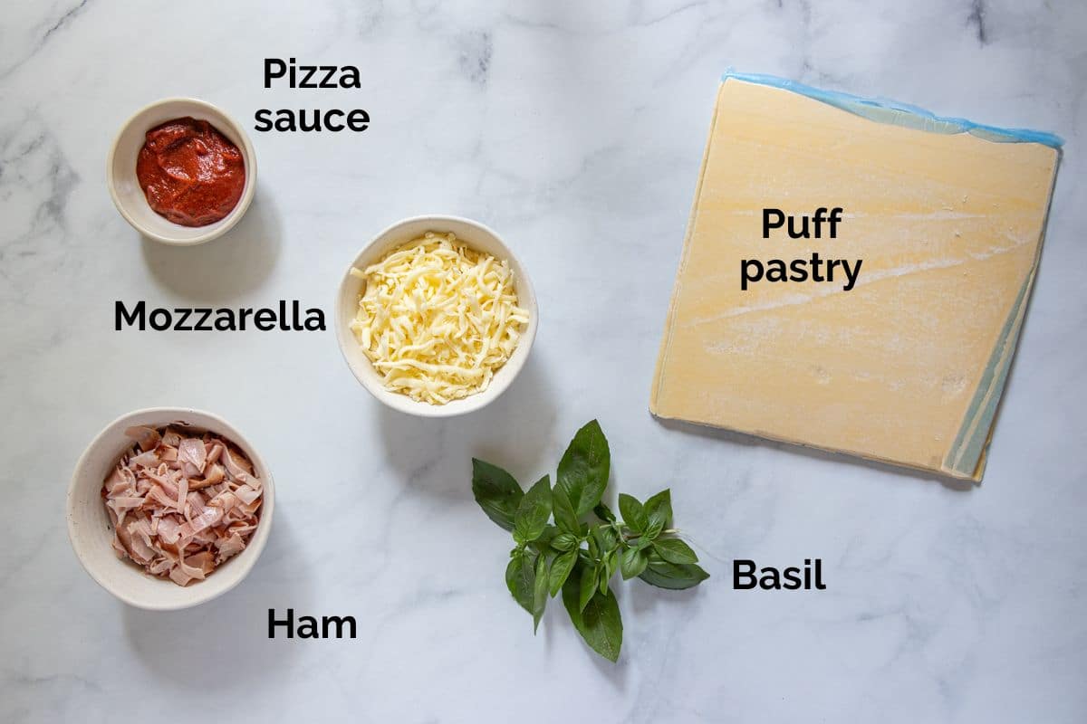 all ingredients for puff pastry pizza scrolls, laid out on a table.