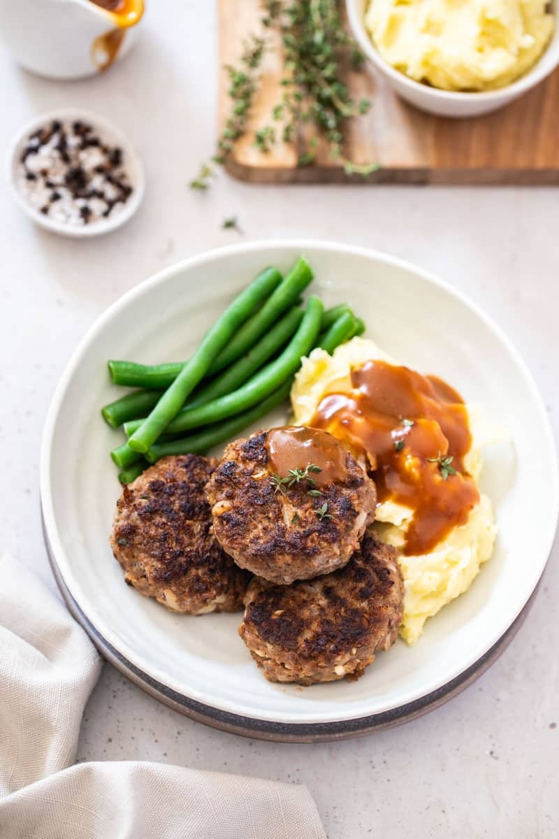 a dinner plate on a table, with rissoles and vegetables.