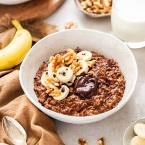 chocolate porridge in a bowl, topped with nuts and banana.