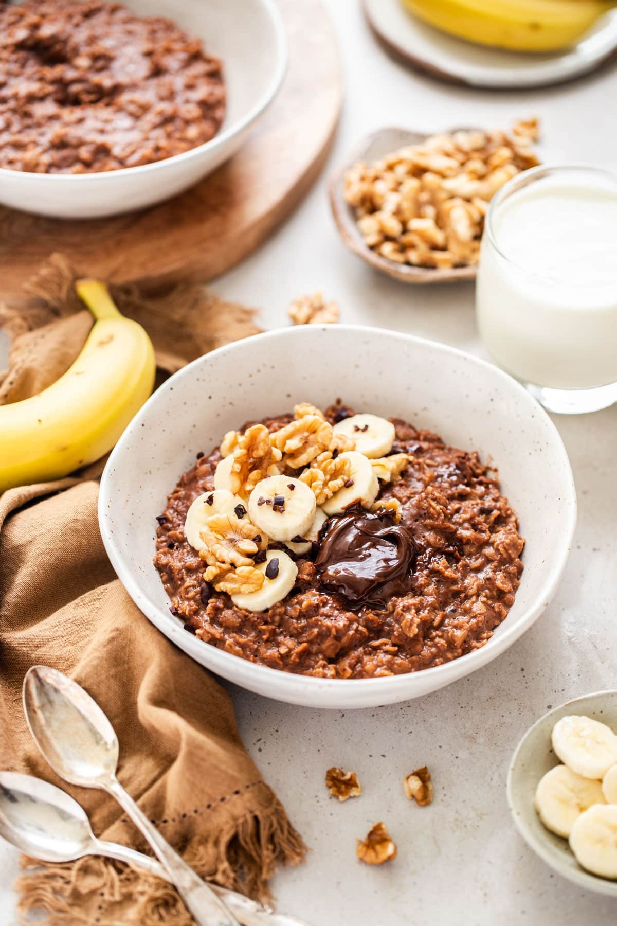 a bowl filled with chocolate porridge, topped with nuts and banana.