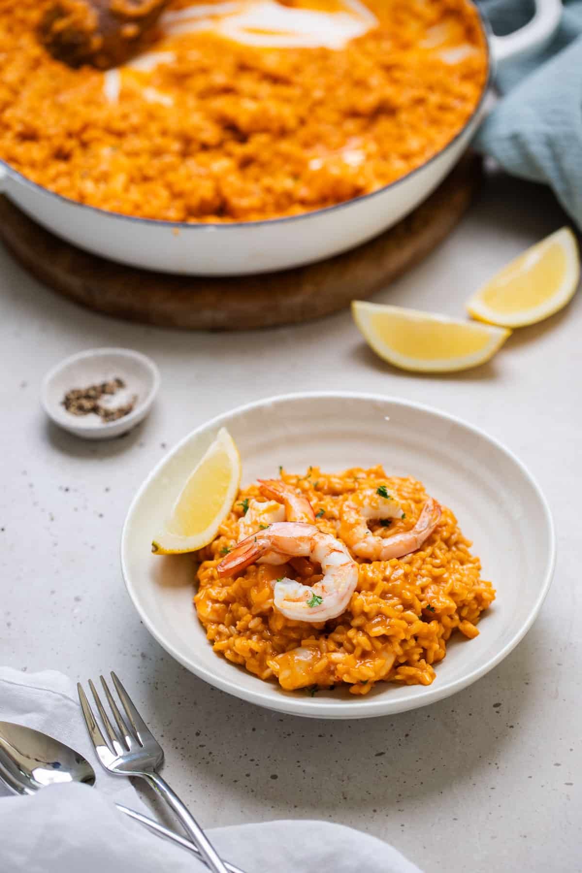 a bowl of finished risotto on a table with lemon wedges.