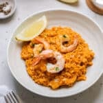 a bowl of finished risotto topped with prawns and lemon.