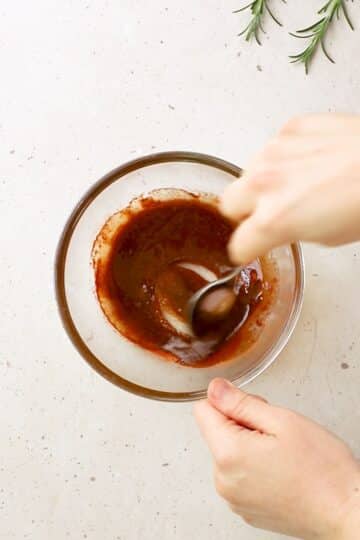 hands mixing chicken seasoning in a bowl.