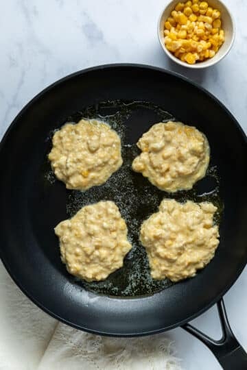 creamed corn fritters, cooking in a pan.