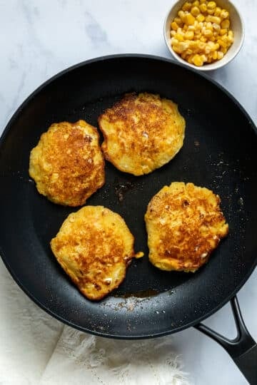 finished corn fritters in a frying pan.