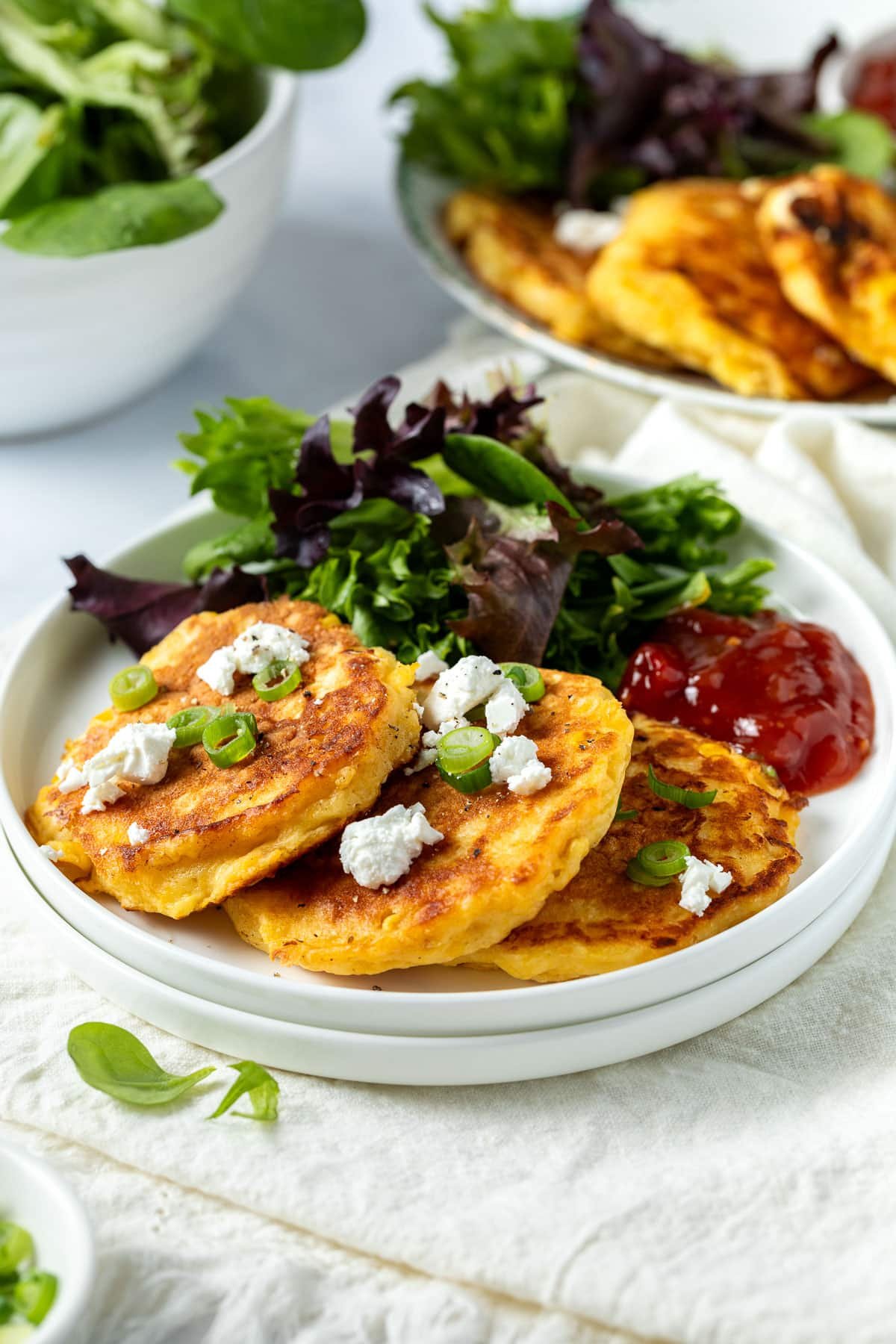 creamed corn fritters arranged on a plate, topped with crumbled feta.