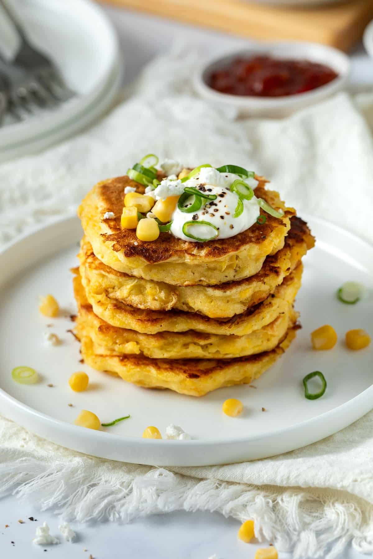 a plate of corn fritters topped with feta and spring onion slices.