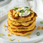 a plate of corn fritters topped with feta and spring onion slices.