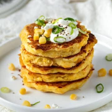 a plate of corn fritters topped with feta and spring onion slices.