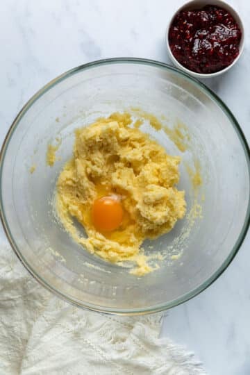 a glass bowl with creamed butter. There is an egg on top.