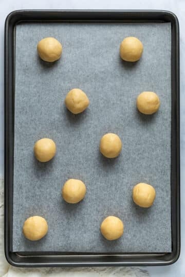 biscuit dough rolled into small balls and arranged on a lined baking tray.