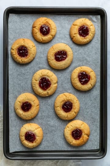 Finished jam drop biscuits, arranged on a baking tray.
